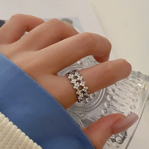 Elegant silver flower ring with pearls and zircons worn on hand holding a glass cup