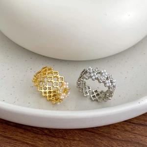 Detail of openwork flower rings with small pearls in gold and silver plating