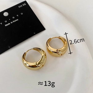 Detail of 2.6cm gold hoop earrings with 925 silver needles on a minimalist white tray
