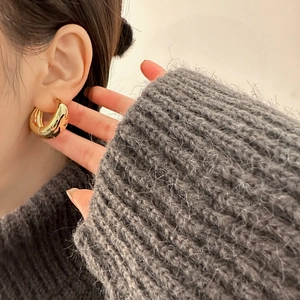 Detailed view of chunky gold hoop earrings with polished finish worn on the ear
