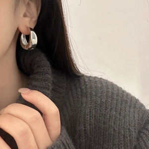 Minimalist silver C-shaped metal hoop earrings shown on model with elegant mirror finish