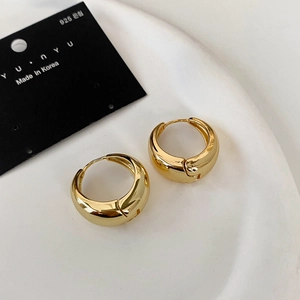 Detailed macro of thick gold-plated hoop earrings with 925 sterling silver pins on ceramic
