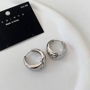Detailed view of polished silver hoop earrings with s925 posts on a white tray