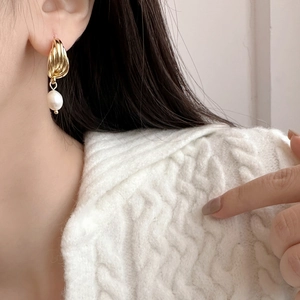 Gros plan d'une boucle d'oreille en perle vintage avec spirale dorée sur un mannequin
