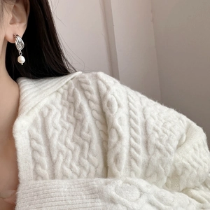 Détail de boucles d'oreilles torsadées en argent avec perles d'eau douce portées sur un pull blanc