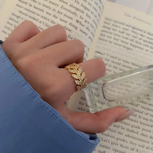 Elegant gold leaf ring with micro-pave crystals shown on finger with classic book background