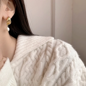 Boucles d'oreilles créoles torsadées dorées avec perle d'eau douce sur mannequin en pull