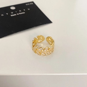 Close-up of a gold leaf ring with white zircon stones on a white and black background