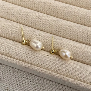 Macro detail of elegant gold-plated freshwater pearl stud earrings on linen texture