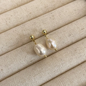 Close-up of Baroque freshwater pearl earrings with gold-plated studs on a velvet tray