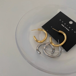 Matte C-shaped irregular earrings in gold and silver finish on a display tray