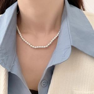 Close-up of a classic white pearl necklace with round pearls on a female model