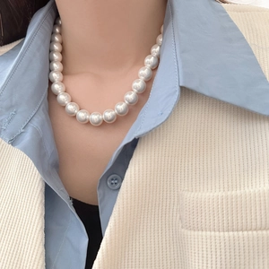 Close-up of large round white pearl necklace with glossy finish on a female model