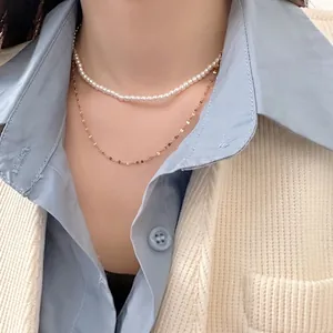 Layered 4mm white pearl necklace with gold chain set on model in blue shirt