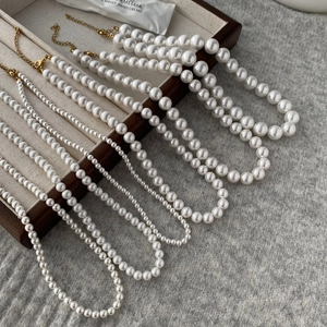 Multiple sizes of round pearl necklaces with gold lobster clasps on a jewelry tray