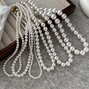 Detail of round pearl necklaces in various sizes on a wooden jewelry display tray