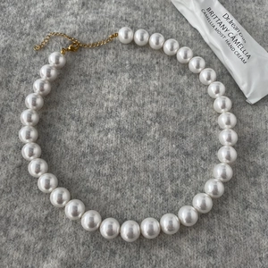 Macro shot of large round white pearls with golden lobster clasp and extender chain
