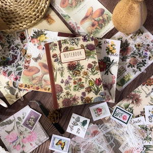 Vintage floral scrapbooking set with journal notebook, stickers, and tweezers on wood
