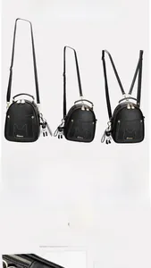 Detail of black mini backpack with golden hardware and cute bear charm pendant