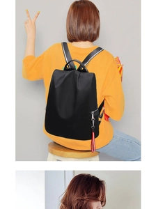 Rückansicht schwarzer Nylon-Rucksack mit rotem Quasten-Detail am Model im gelben Shirt