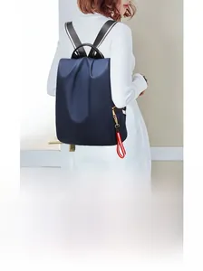 Detailansicht eines blauen Nylon-Rucksacks mit rot-weißem Anhänger an einem Modell