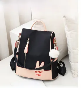 Close-up of contrast color oxford backpack with pink rabbit ears and fluffy ball charm