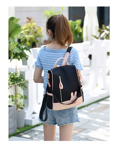 Detail of oxford backpack featuring pink bunny ears design and white pompom charm