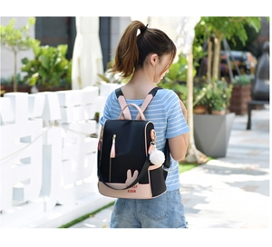 Detail of black and pink oxford backpack featuring cute bunny ears and plush pendant charm
