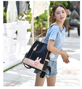 Outdoor lifestyle shot of a black Oxford backpack with pink accents and plush charm