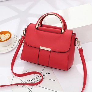 Fashionable red faux leather handbag with gold handle and strap shown in lifestyle setting