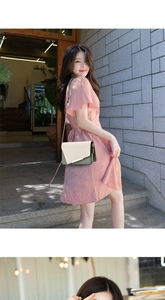 Detalle del bolso bandolera bicolor con cadena dorada sobre un vestido de gasa rosa