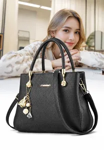 Détail d'un sac à main en cuir grainé noir avec finitions dorées et breloque perle