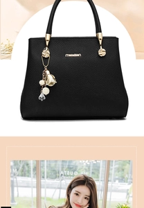 Détail d'un sac à main en cuir noir avec logo doré et pendentif floral décoratif