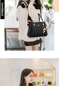 Détail du sac à main noir en cuir grainé avec anse ronde en métal et pendentif doré
