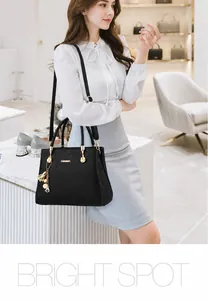 Détail d'un sac à main en cuir noir avec logo doré et pendentif floral élégant