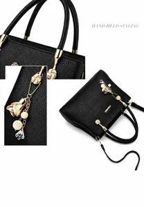 Vue détaillée du sac à main noir en cuir grainé avec finitions dorées et pendentif fleur