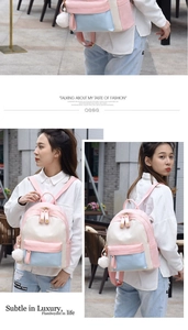 Detail of a color-block backpack featuring a heart zipper and white fur ball pendant