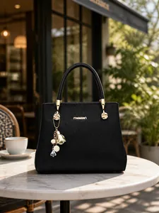 Vue détaillée de face d'un sac à main noir motif litchi avec ornements dorés et charms
