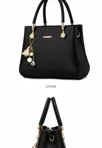 Détail du sac à main noir en cuir grainé avec finitions dorées et pendentif perle