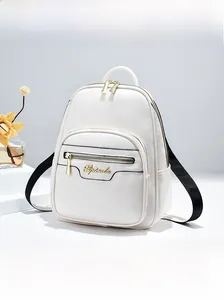 Close-up of a white leather mini backpack showing golden metal logo and zip pocket detail