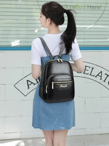 Detailed view of women's black leather backpack featuring gold hardware and logo