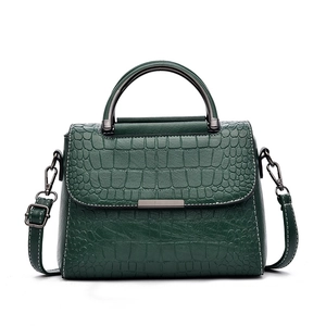 Deep green crocodile embossed handbag with metallic handles and adjustable shoulder strap