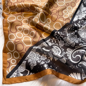 Close-up of silk scarf featuring paisley patterns and yellow circular motifs on faux silk
