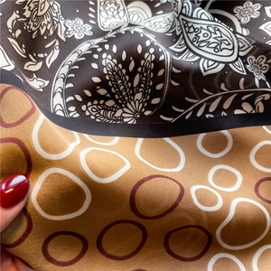 Detail of paisley and geometric ring patterns on smooth satin silk square scarf