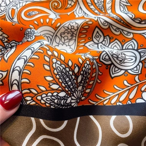 Detailed macro view of orange paisley pattern silk scarf with satin glossy texture