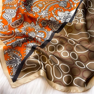 Close-up of paisley silk scarf featuring orange and brown contrast patterns and fine edges