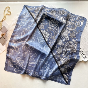 Detail of blue and white paisley silk scarf with geometric circle patterns and glossy texture