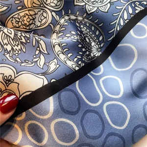 Detail of silk scarf with grey-blue paisley floral pattern and white circular lines