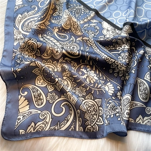 Detail of paisley and geometric circles on blue and beige satin scarf with black borders