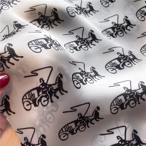 Detailed view of lightweight silk scarf featuring classic black carriage pattern on cream fabric